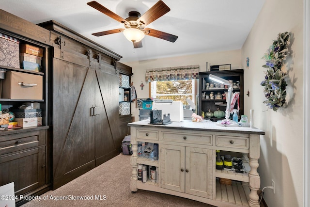 bar featuring ceiling fan, a barn door, carpet floors, and cream cabinets