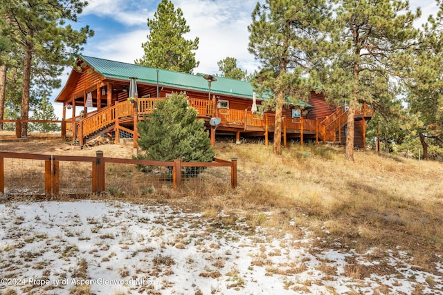 snow covered rear of property with a wooden deck