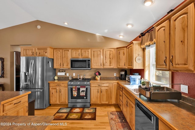 kitchen featuring sink, stainless steel appliances, lofted ceiling, and light hardwood / wood-style floors