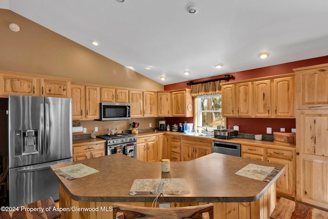 kitchen featuring sink, a breakfast bar area, light brown cabinetry, a kitchen island, and stainless steel appliances