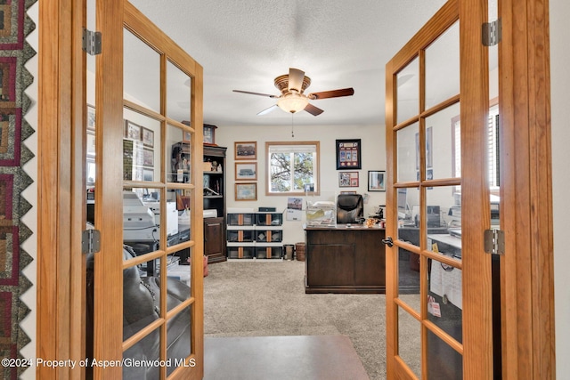 carpeted home office with ceiling fan, a textured ceiling, and french doors