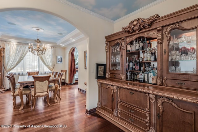 81 River Park Ln, Carbondale, CO 81623 - dining area featuring arched walkways, a chandelier, a dry bar, dark wood-type flooring, and baseboards