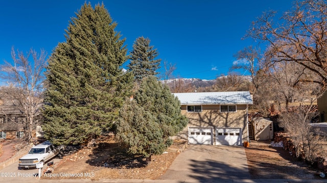 view of front of property featuring a garage, metal roof, and concrete driveway