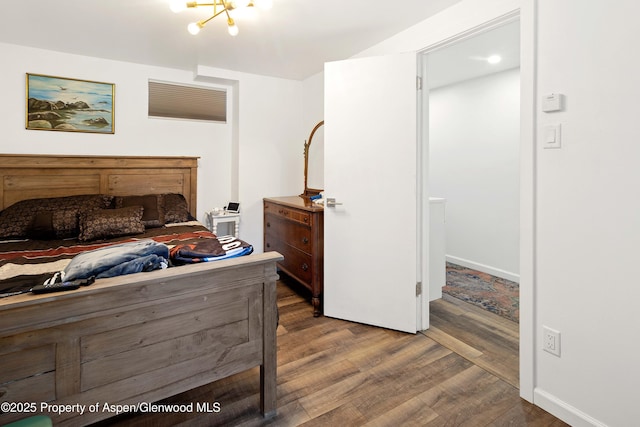 bedroom featuring a chandelier, baseboards, and wood finished floors