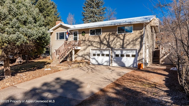 view of front of property with a chimney, concrete driveway, stairway, an attached garage, and metal roof