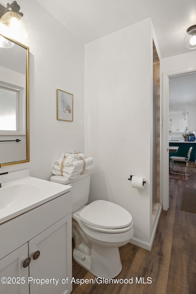 bathroom featuring toilet, wood finished floors, vanity, and a shower stall