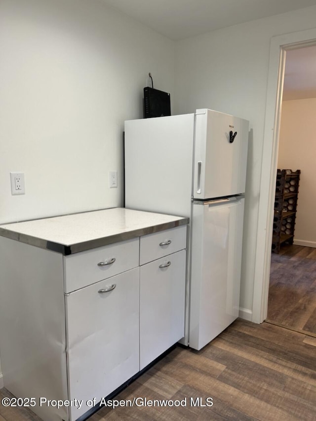 kitchen featuring white cabinetry, dark wood finished floors, light countertops, and freestanding refrigerator