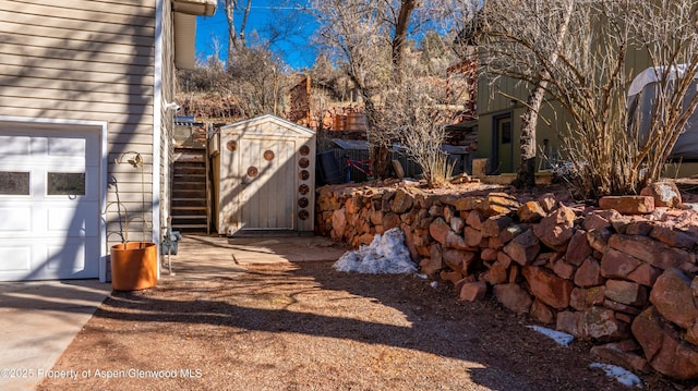 view of yard featuring a garage, a storage unit, and an outdoor structure