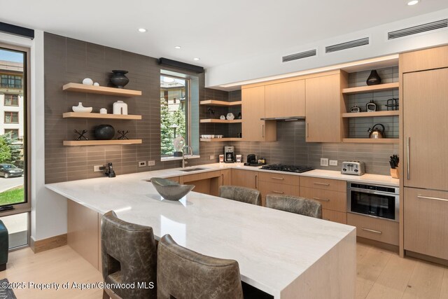 130 Wood Rd Unit 264, Snowmass Village, CO 81615 - kitchen featuring open shelves, light wood-style floors, a breakfast bar area, backsplash, and recessed lighting