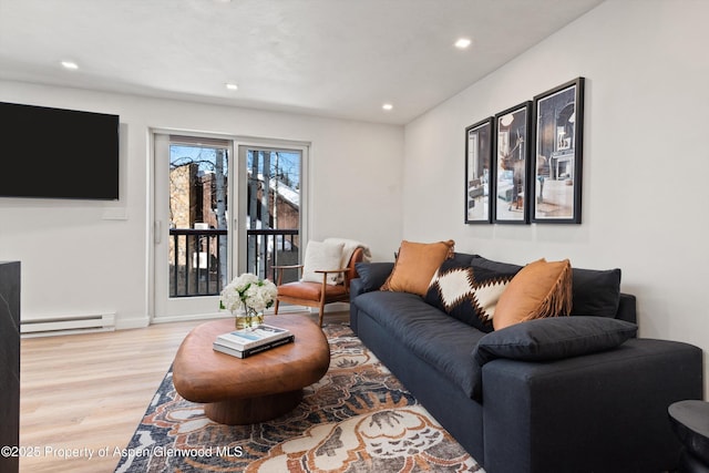 living room with light hardwood / wood-style floors and a baseboard heating unit