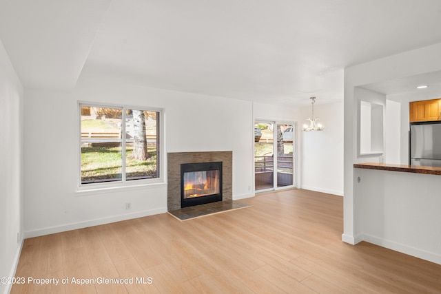 35 Lower Woodbridge Rd Unit B107, Snowmass Village, CO 81615 - unfurnished living room featuring a chandelier, light wood-type flooring, baseboards, and a tile fireplace