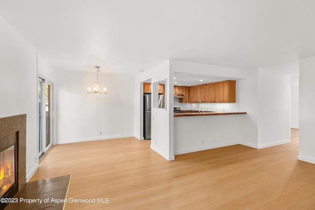 35 Lower Woodbridge Rd Unit B107, Snowmass Village, CO 81615 - unfurnished living room featuring a chandelier, light wood-type flooring, a fireplace, and baseboards