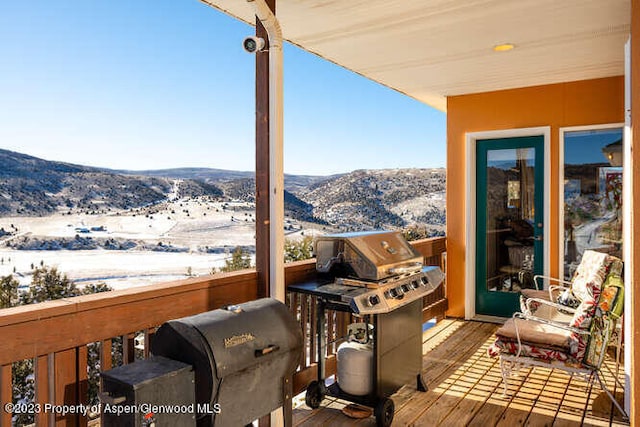 snow covered deck with a mountain view