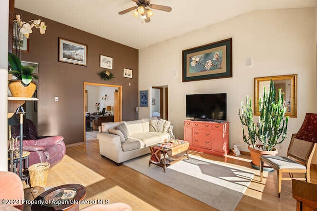 living room with ceiling fan, lofted ceiling, and light hardwood / wood-style flooring