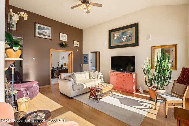 living room with ceiling fan, lofted ceiling, and light hardwood / wood-style flooring