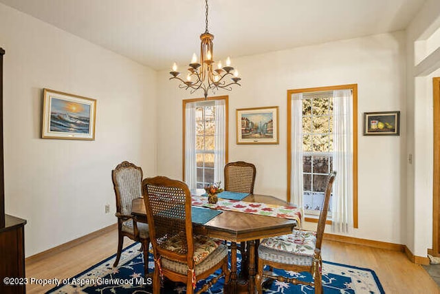 dining area with light hardwood / wood-style flooring, an inviting chandelier, and a wealth of natural light