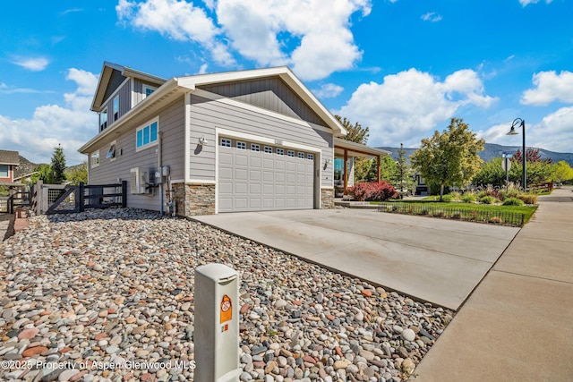 510 S Wildhorse Dr, New Castle, CO 81647 - view of home's exterior featuring a garage, a gate, concrete driveway, stone siding, and a mountain view