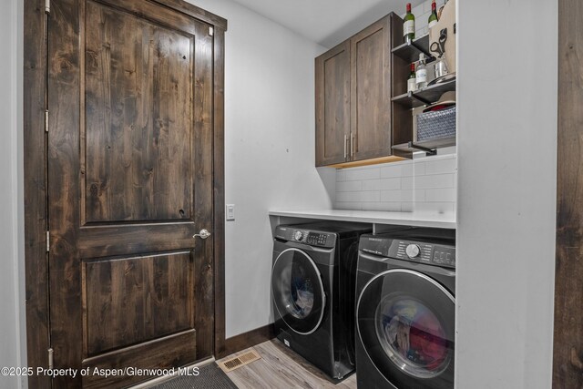 510 S Wildhorse Dr, New Castle, CO 81647 - washroom featuring cabinet space, washing machine and clothes dryer, baseboards, and light wood-type flooring