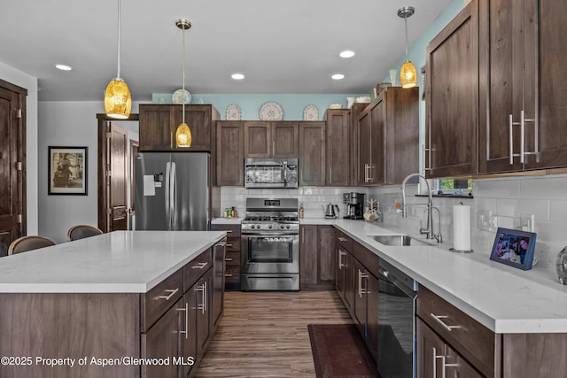 510 S Wildhorse Dr, New Castle, CO 81647 - kitchen featuring appliances with stainless steel finishes, a sink, a kitchen island, wood finished floors, and decorative backsplash