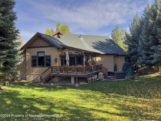 back of property featuring a wooden deck, a yard, and a hot tub