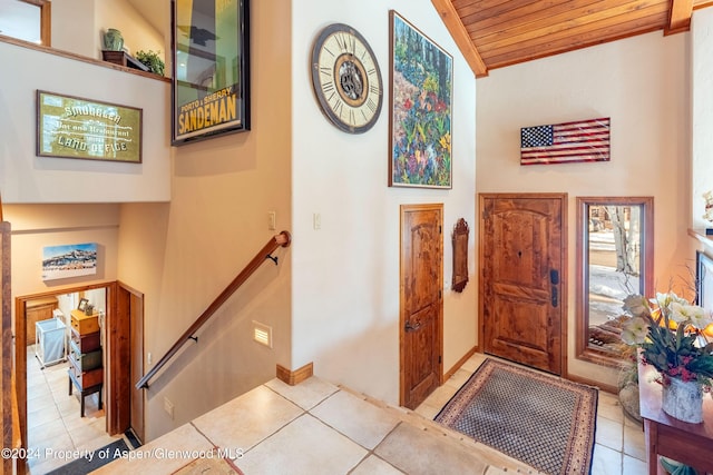 entryway with light tile patterned floors, wooden ceiling, and high vaulted ceiling