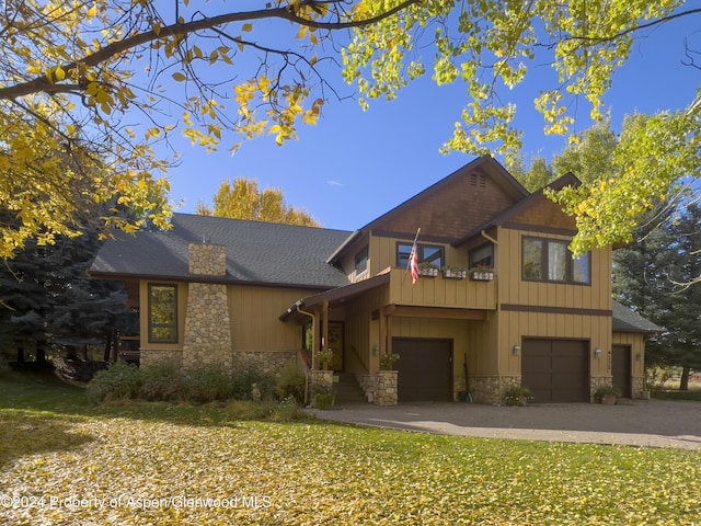 view of front of property featuring a balcony, a front lawn, and a garage