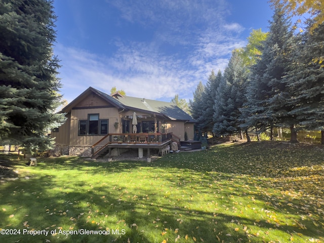 rear view of property featuring a lawn and a wooden deck