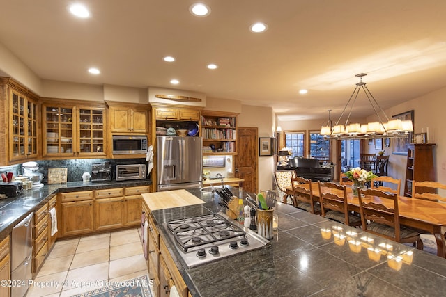 kitchen featuring tasteful backsplash, pendant lighting, a notable chandelier, and appliances with stainless steel finishes