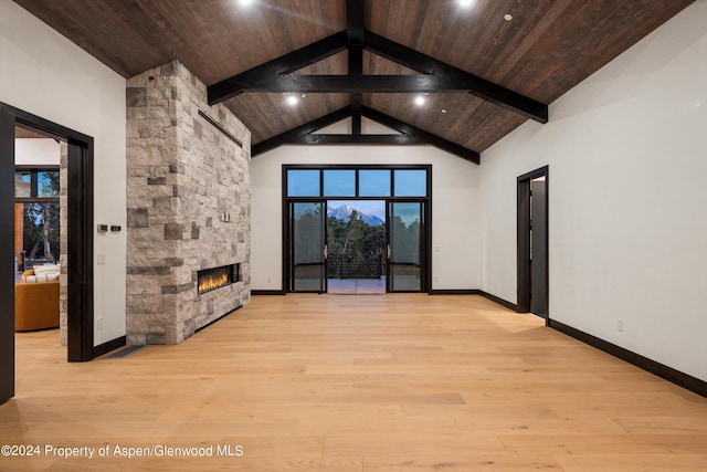 unfurnished living room featuring a stone fireplace, beamed ceiling, high vaulted ceiling, and light wood-type flooring