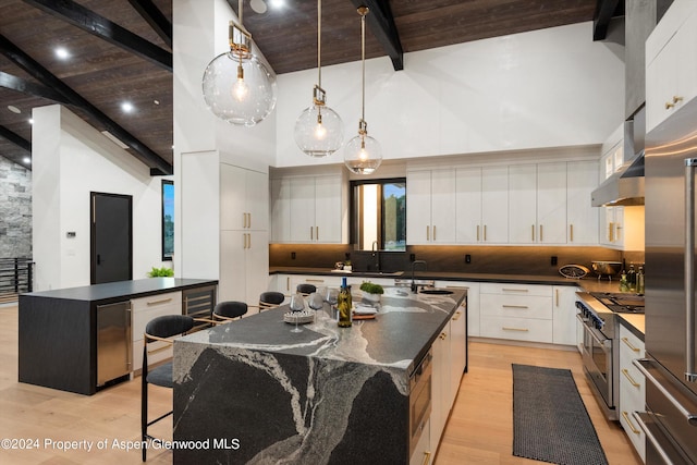 kitchen with white cabinetry, beamed ceiling, a spacious island, and high end appliances