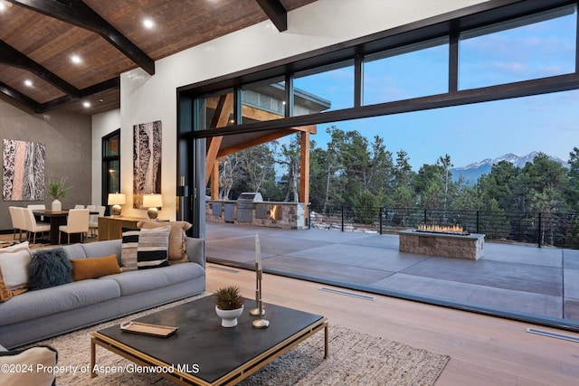 living room with a mountain view, a high ceiling, expansive windows, hardwood / wood-style flooring, and beam ceiling