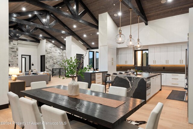 dining room with wooden ceiling, high vaulted ceiling, sink, light wood-type flooring, and beam ceiling