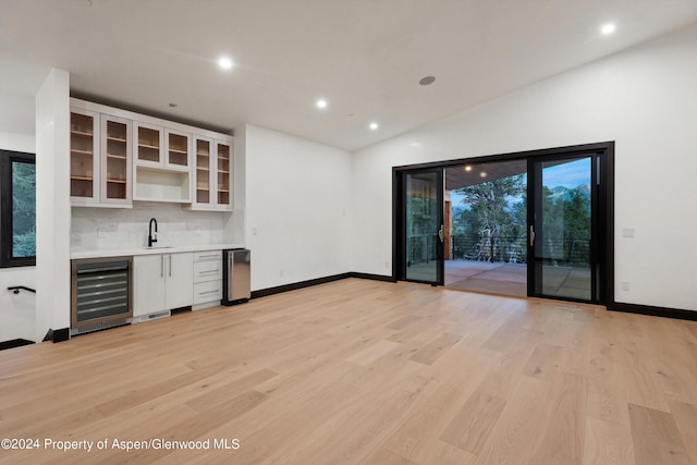 bar featuring wine cooler, decorative backsplash, light hardwood / wood-style floors, and lofted ceiling