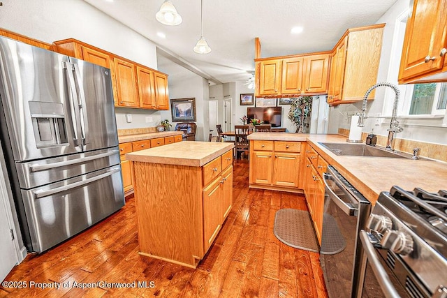 kitchen featuring hardwood / wood-style floors, appliances with stainless steel finishes, a center island, pendant lighting, and sink