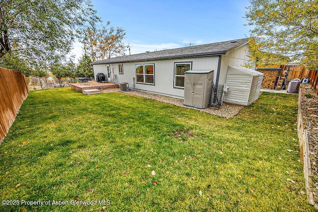 back of property with cooling unit, a deck, a storage shed, and a lawn