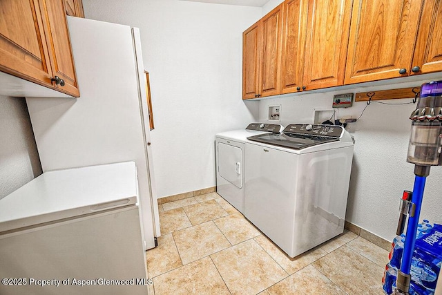 clothes washing area with washer and dryer, cabinets, and light tile patterned floors