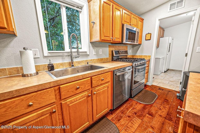 kitchen with plenty of natural light, dark wood-type flooring, appliances with stainless steel finishes, and sink