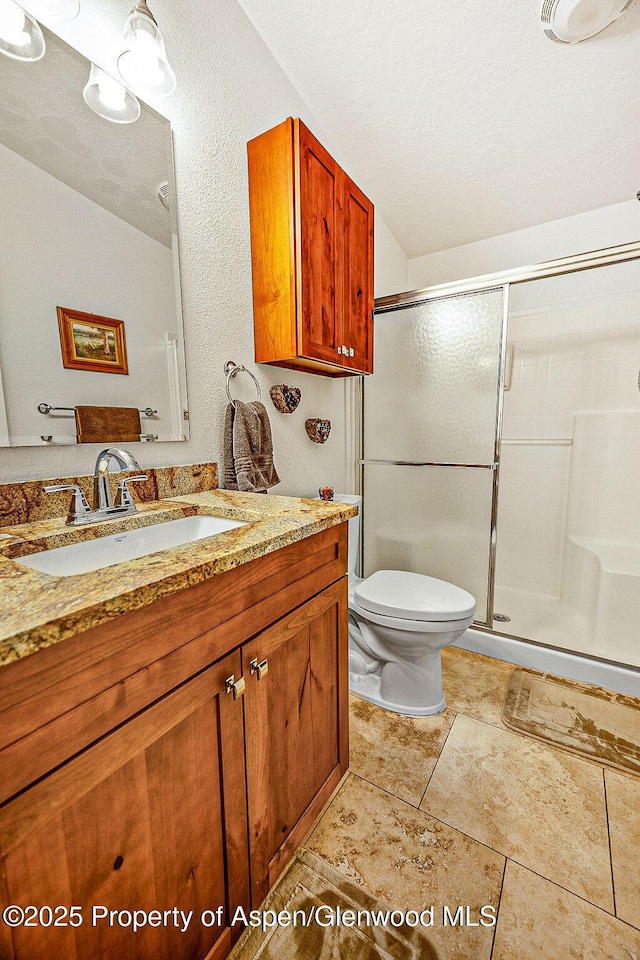 bathroom featuring toilet, a textured ceiling, a shower with shower door, and vanity