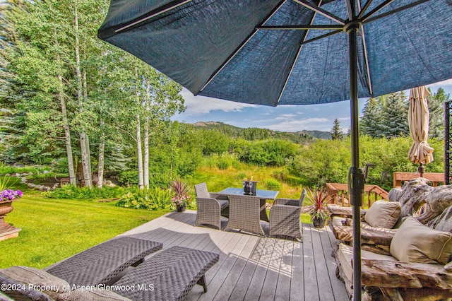 115 Harleston Grn Unit 63, Snowmass Village, CO 81615 - wooden terrace featuring outdoor dining area, a lawn, and a mountain view