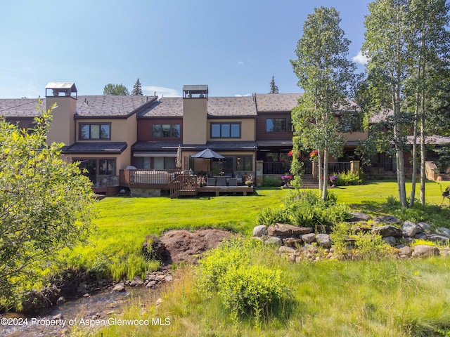 115 Harleston Grn Unit 63, Snowmass Village, CO 81615 - rear view of property featuring a deck, a lawn, stucco siding, and a chimney