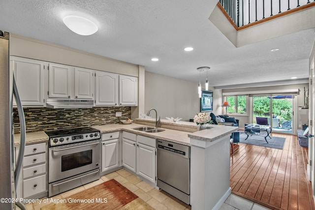 kitchen with sink, backsplash, kitchen peninsula, white cabinets, and appliances with stainless steel finishes