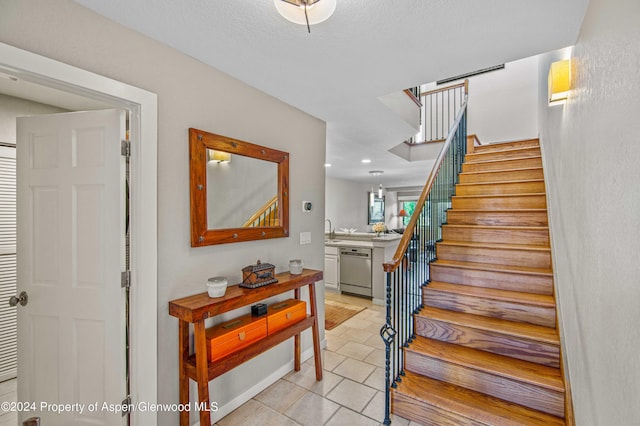 stairs with tile patterned floors and sink