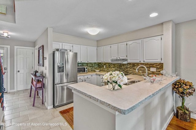 kitchen featuring white cabinets, a kitchen breakfast bar, kitchen peninsula, and stainless steel appliances