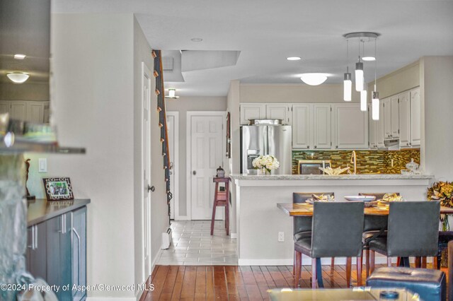 115 Harleston Grn Unit 63, Snowmass Village, CO 81615 - kitchen with stainless steel refrigerator with ice dispenser, hardwood / wood-style floors, a breakfast bar, pendant lighting, and white cabinets