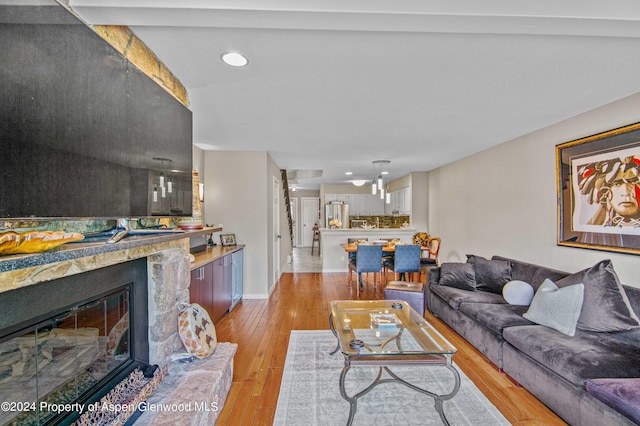 living room with light hardwood / wood-style floors and a stone fireplace