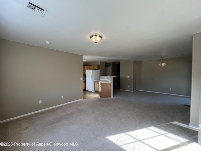 unfurnished living room featuring light carpet and a chandelier