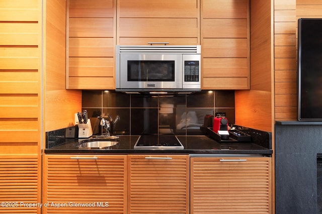 kitchen with black electric cooktop, sink, and decorative backsplash