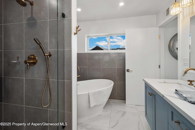 bathroom featuring tile walls, a tile shower, vanity, a freestanding bath, and marble look tile flooring