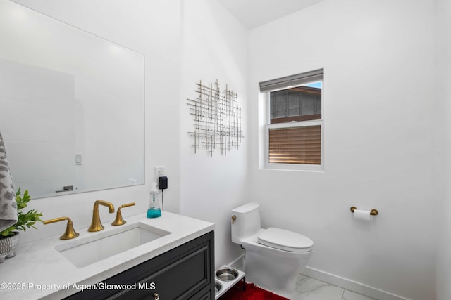 bathroom featuring marble finish flooring, toilet, vanity, and baseboards