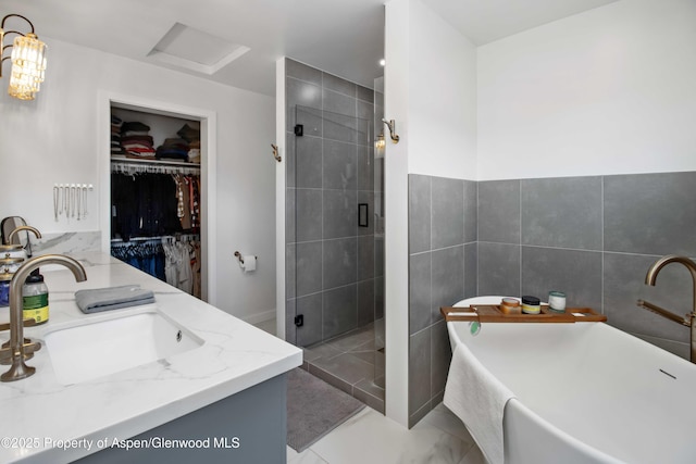 full bath featuring a walk in closet, a shower stall, a freestanding bath, double vanity, and tile walls